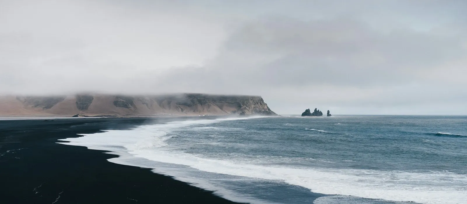 Black volcanic sand meeting the sea representing technology built with purpose